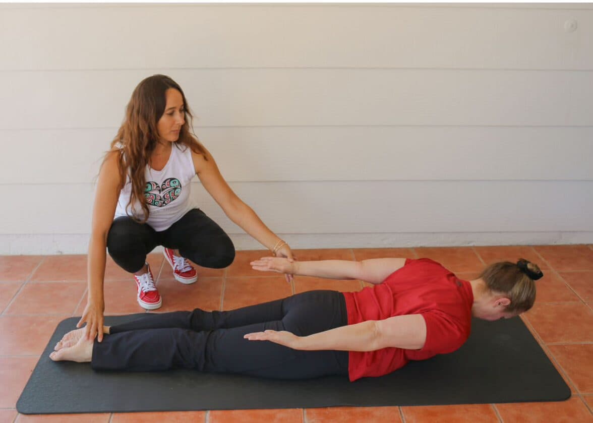 Tracey cueing a client through a prone Pilates extension on a mat